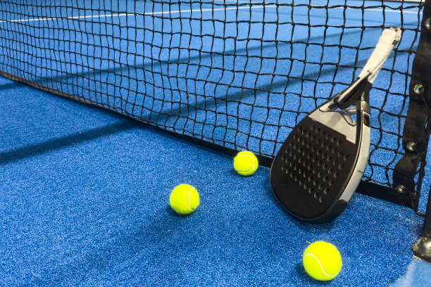 Padel racket and balls beside the net on a padel court